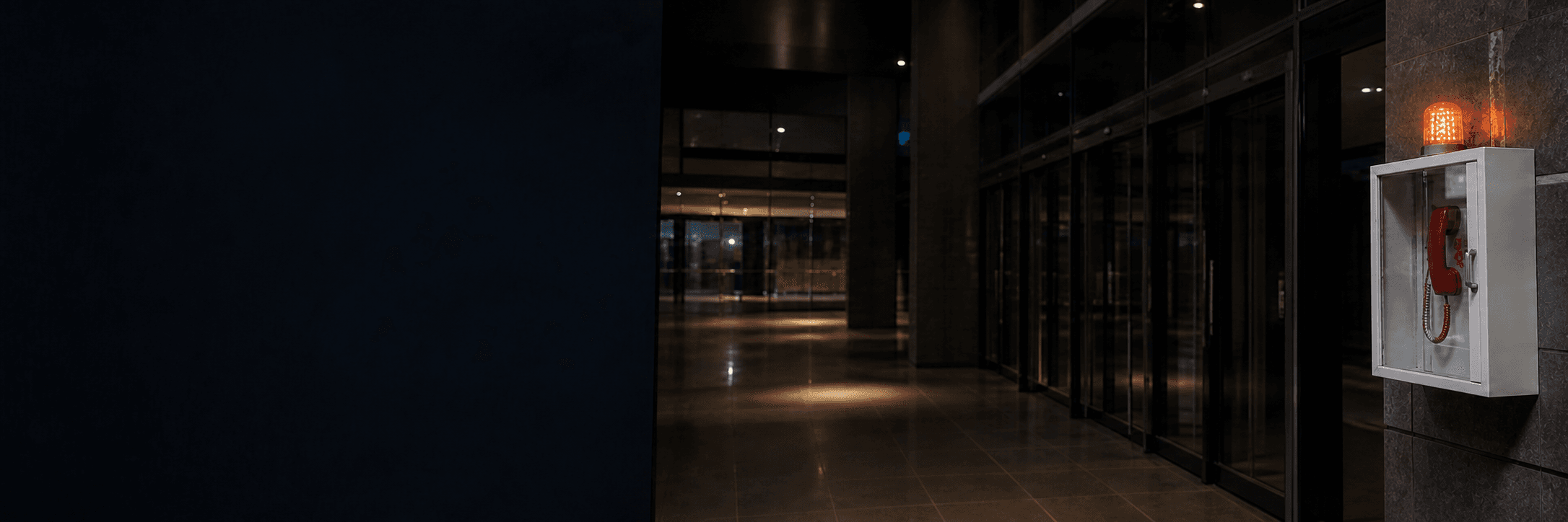 Empty emergency-response corridor with an alert beacon and wall-mounted emergency phone